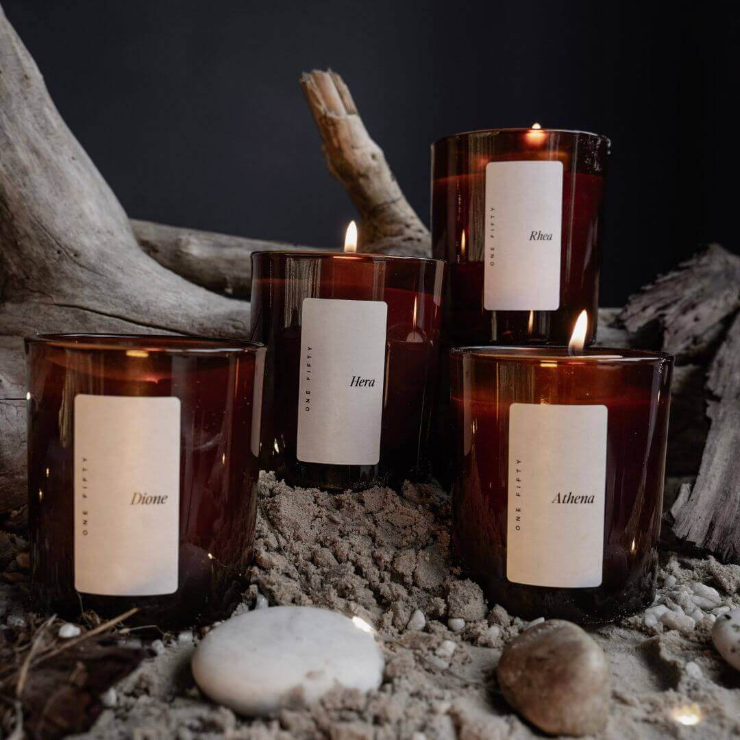 this is an image of four signature collection candles in amber vessels with a cream label on them