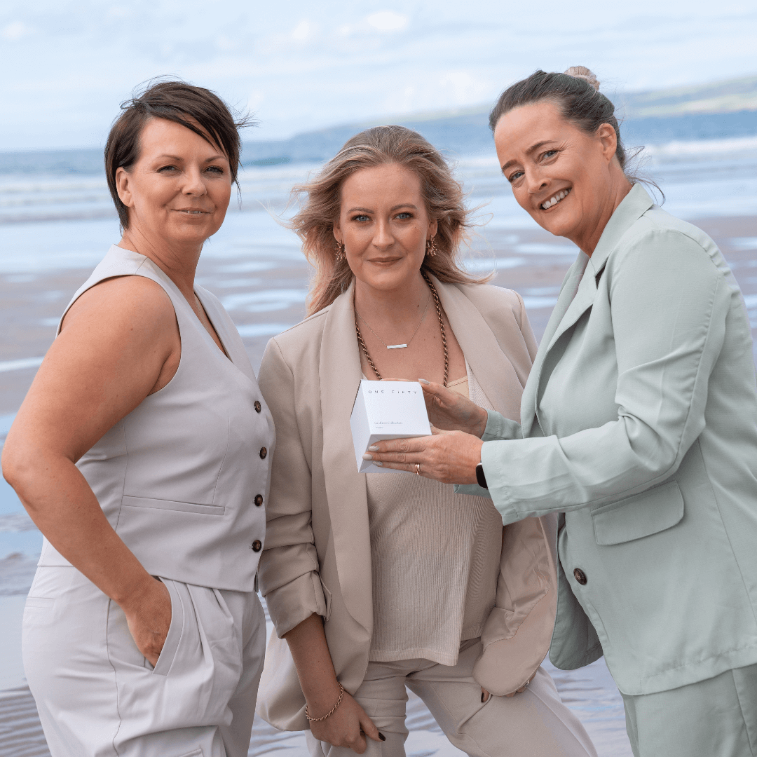 Three female brand owners proudly showcase their new candle box packaging. They stand side by side, holding a beautifully designed box that exudes sophistication. The packaging reflects a blend of creativity and elegance, hinting at the craftsmanship and care that goes into their candle products. The women wear confident smiles, embodying the pride and dedication behind their Irish hand made candles 